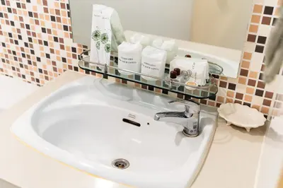 a bathroom sink with a glass shelf above it at Summit Pavilion Hotel in Bangkok