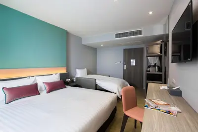 a hotel room with two beds and a table at Hotel Tranz in Bangkok