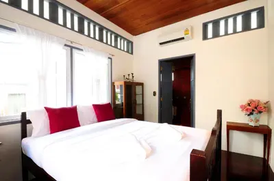 a bedroom with a large white bed with red pillows at Baan Noppawong in Bangkok