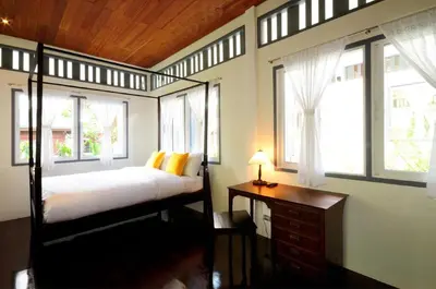 a bedroom with a bed and a desk and windows at Baan Noppawong in Bangkok