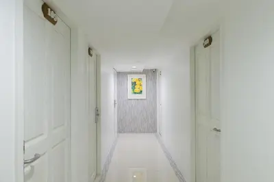 a hallway with two white doors and a painting on the wall at Sabai Sathorn Service Apartment in Bangkok