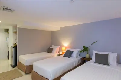two beds in a hotel room with white sheets at Sabai Sathorn Service Apartment in Bangkok