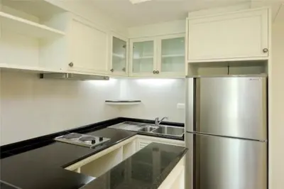a kitchen with white cabinets and a stainless steel refrigerator at Sabai Sathorn Service Apartment in Bangkok