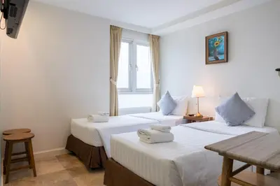 two beds in a room with a window at Sabai Sathorn Service Apartment in Bangkok