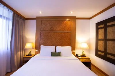 a bedroom with a large white bed with two lamps at The Tarntawan Hotel Surawong Bangkok in Bangkok