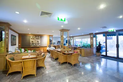 a restaurant with wicker chairs and tables in a room at The Tarntawan Hotel Surawong Bangkok in Bangkok