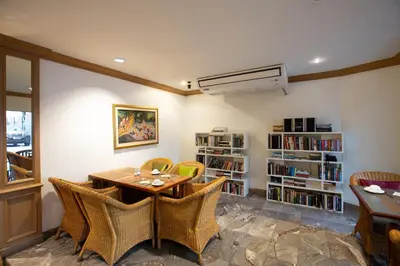 a dining room with a table and chairs and a book shelf at The Tarntawan Hotel Surawong Bangkok in Bangkok