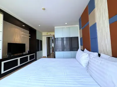 a bedroom with a large white bed with a television at The Sunreno Hotel Bangkok in Bangkok