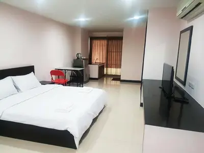 a bedroom with a bed and a desk and a television at Mok Mek 72 in Bangkok