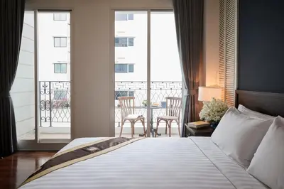 a bedroom with a bed and a balcony with chairs at The Rose Residence, Bangkok in Bangkok