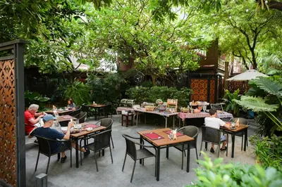 a group of people sitting at tables in a restaurant at The Rose Residence, Bangkok in Bangkok