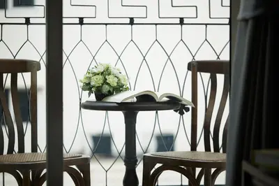 a table with a vase of flowers and two chairs at The Rose Residence, Bangkok in Bangkok