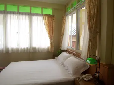 a bedroom with a bed and a window with a phone at Baan Dinso in Bangkok