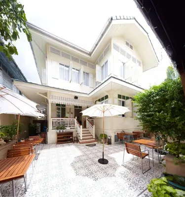 a building with a patio with tables and umbrellas at Baan Dinso in Bangkok