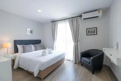 a bedroom with a bed and a chair and a window at Ratchadamnoen Residence in Bangkok