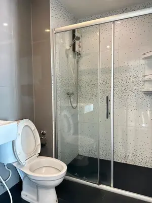 a bathroom with a toilet and a glass shower at DB Plus 2 in Bangkok