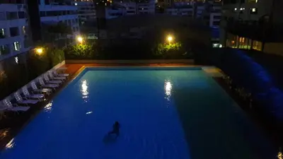a person standing in a swimming pool at night at Panoramic City View Room at Silom in Bangkok