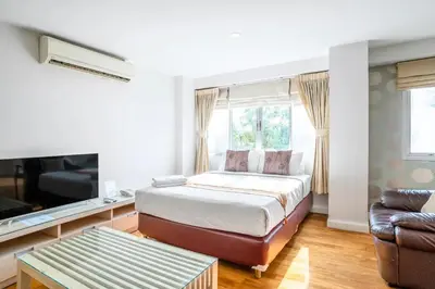 a bedroom with a bed and a tv and a couch at Nara Suite Residence Bangkok in Bangkok