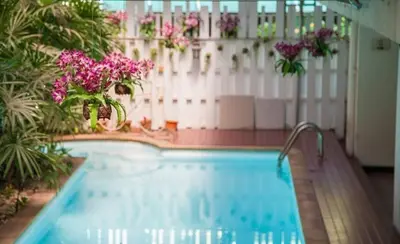 a swimming pool with pink flowers and a white fence at Nara Suite Residence Bangkok in Bangkok