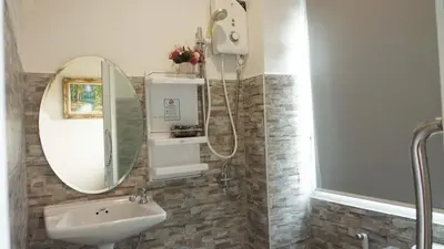 a bathroom with a shower and a sink and a mirror at Westgate Residence Hotel in Ban Bang Kho