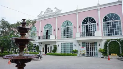a pink building with a fountain in front of it at Westgate Residence Hotel in Ban Bang Kho