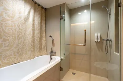 a bathroom with a shower and a tub and a glass shower stall at Greenview Ekkamai10 Suite in Bangkok