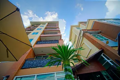 a tall building with a palm tree in front of it at Greenview Ekkamai10 Suite in Bangkok