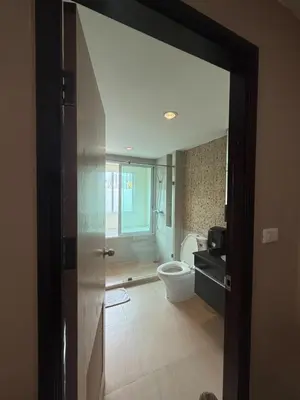 a bathroom with a toilet and a sink and a door at Greenview Ekkamai10 Suite in Bangkok
