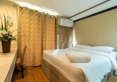 a bedroom with a large white bed with a window at Greenview Ekkamai10 Suite in Bangkok