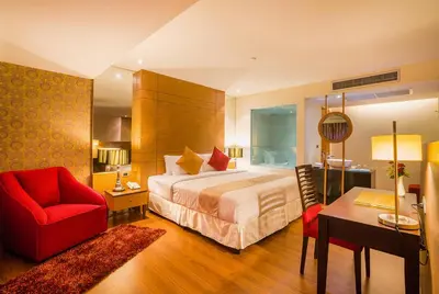 a hotel room with a bed and a red chair at Grand Lord Boutique Hotel -Srinakarin in Bangna