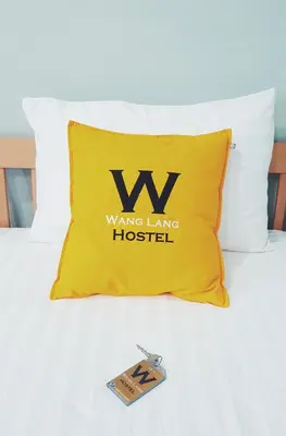 a yellow pillow on a bed with a living long hospital at Wang Lang Hostel in Bangkok
