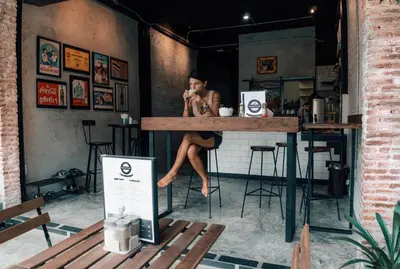 a woman sitting at a bar talking on a cell phone at Sawatdee Guesthouse the Original in Bangkok