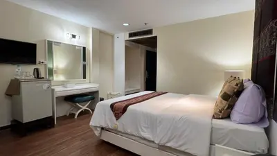 a bedroom with a bed and a desk and a television at Fortuna Hotel in Bangkok