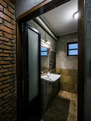 a bathroom with a sink and a brick wall at Zeds Hostel Bangkok in Bangkok