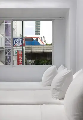 a white couch in a room with a window at Nantra Silom in Bangkok