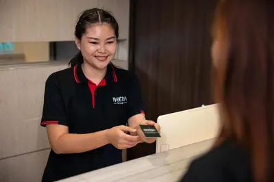 a woman holding a cell phone in front of a counter at Nantra Silom in Bangkok