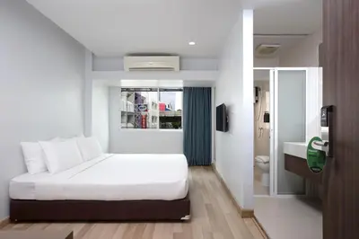a bedroom with a white bed and a bathroom at Nantra Silom in Bangkok