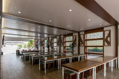 a restaurant with wooden tables and windows at A Room Bangkok Sathorn in Bangkok