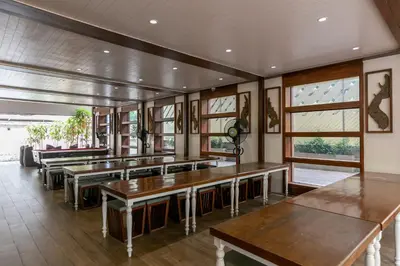 a dining room with wooden tables and windows at A Room Bangkok Sathorn in Bangkok