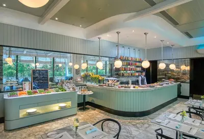 a restaurant with a chef standing behind a counter at Oriental Residence Bangkok in Bangkok