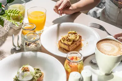 a table with two plates of food and a cup of coffee at The Okura Prestige Bangkok in Bangkok