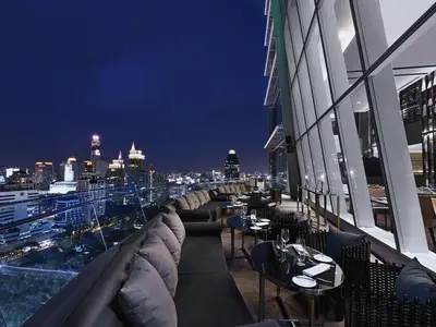 a restaurant with couches and tables on a balcony at night at The Okura Prestige Bangkok in Bangkok