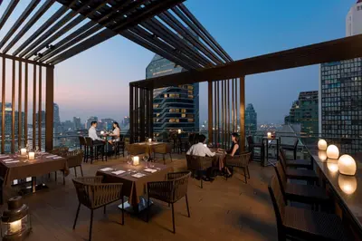 a restaurant with tables and chairs and a view of the city at The Okura Prestige Bangkok in Bangkok