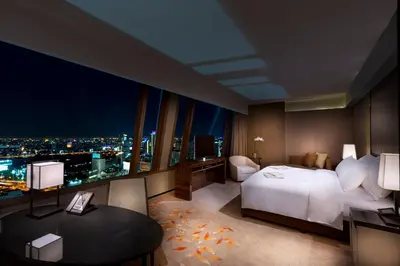 a hotel room with a bed and a desk and a window at The Okura Prestige Bangkok in Bangkok