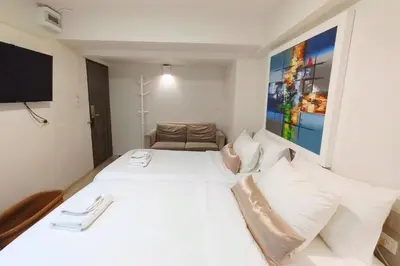 a bedroom with a white bed and a television at Sawasdee House in Bangkok