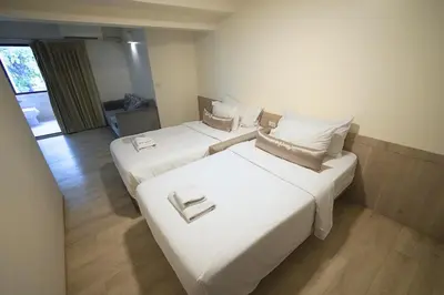 two beds in a room with white sheets and pillows at Sawasdee House in Bangkok