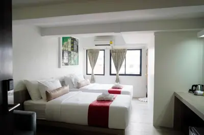 a white bedroom with a bed and a couch at Sawasdee House in Bangkok