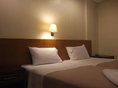 a bedroom with two beds with white pillows and a lamp at Lodge 61 Hotel in Bangkok