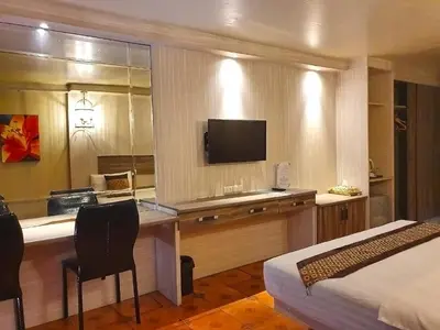 a hotel room with a desk with a television and a bed at The Montana Lodge-Sathorn in Bangkok