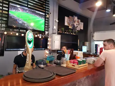 two people sitting at a counter in a restaurant with a bar at Casa Picasso Near Chabad House in Bangkok